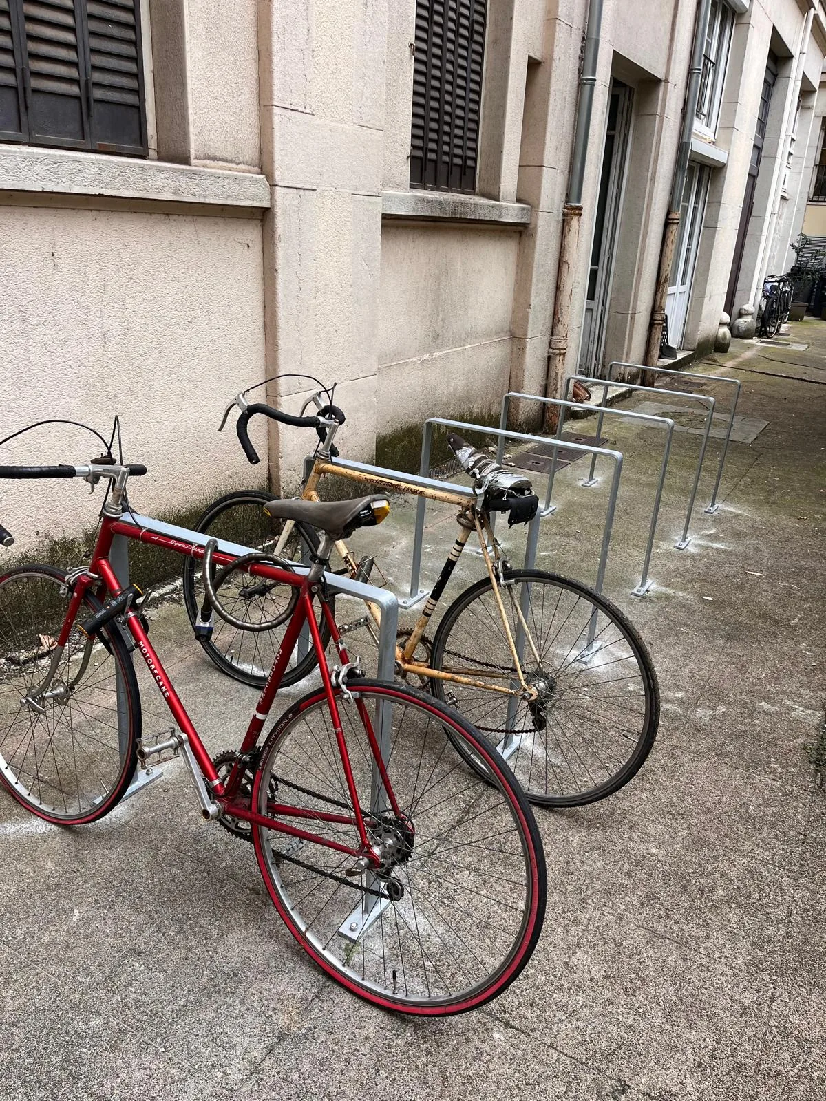 Rangée d'arceaux Recto dans une cour d'immeuble à Lyon, deux vélos attachés