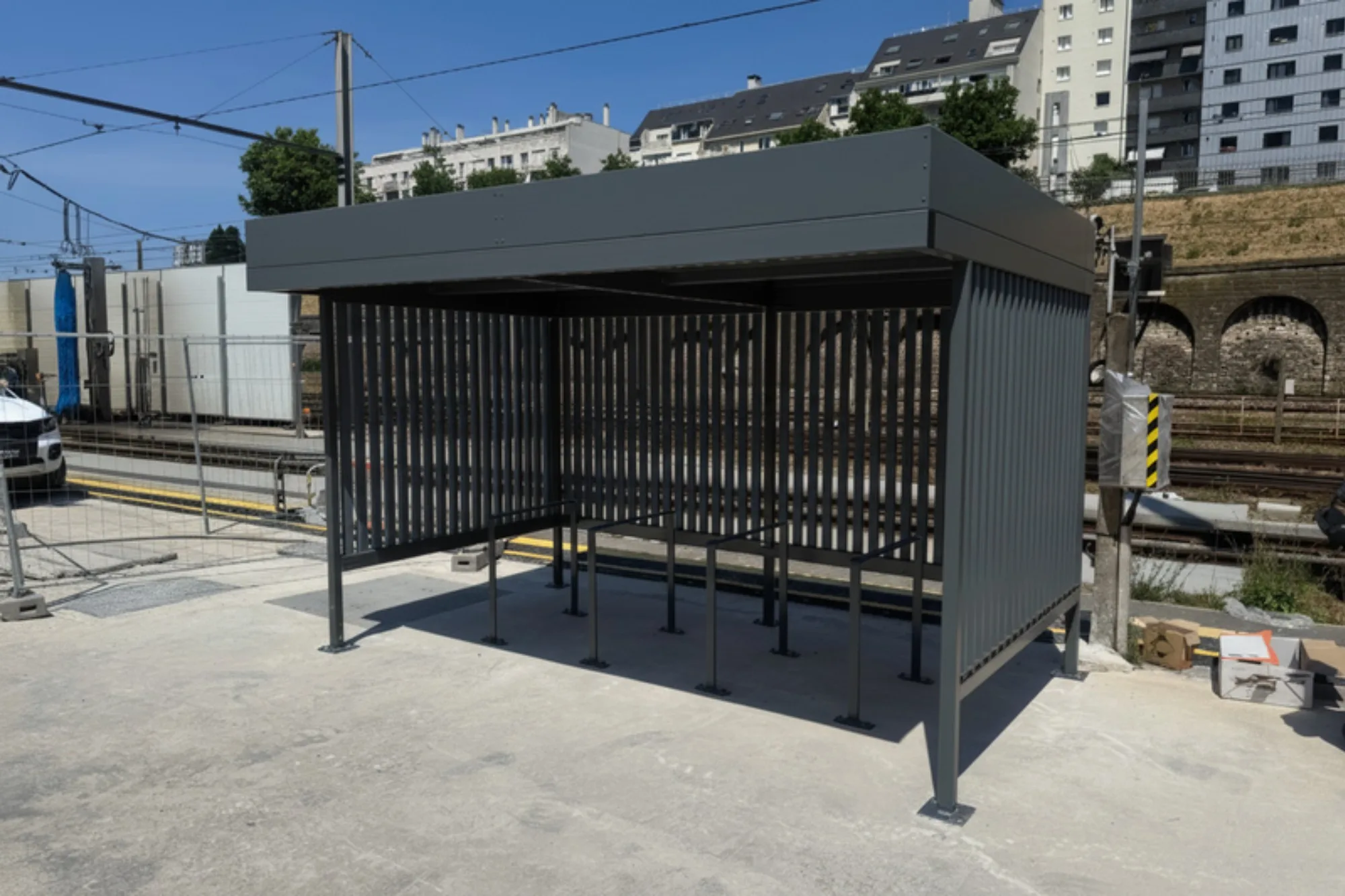Abri vélo à toiture végétalisée installé le long des voies dans une gare SNCF