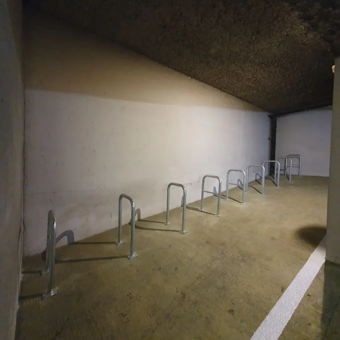 Local vélo avec arceaux déployé dans le parking d’une ancienne copropriété