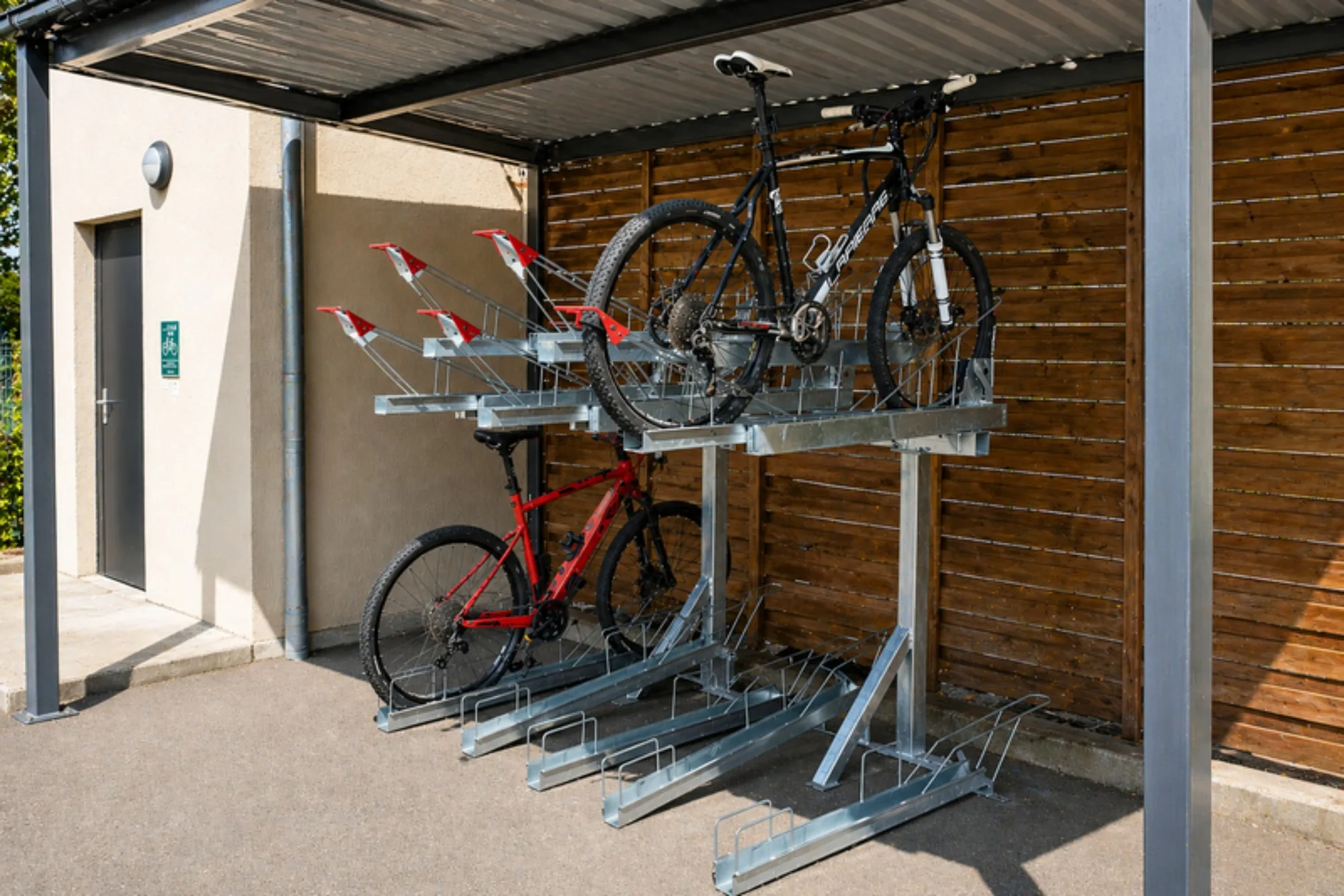 Rack à vélos double étage avec les vélos en place, installé sous un auvent